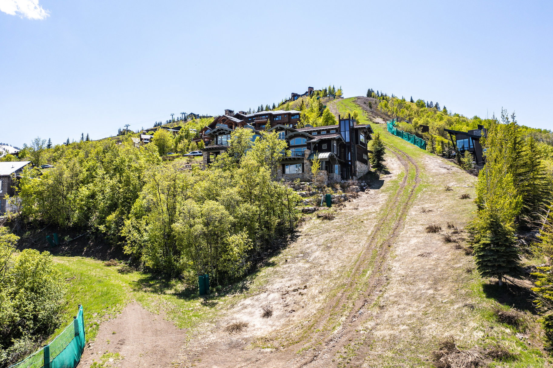Hillside property featuring multiple residences with varied architectural styles, surrounded by abundant mature trees and natural green spaces