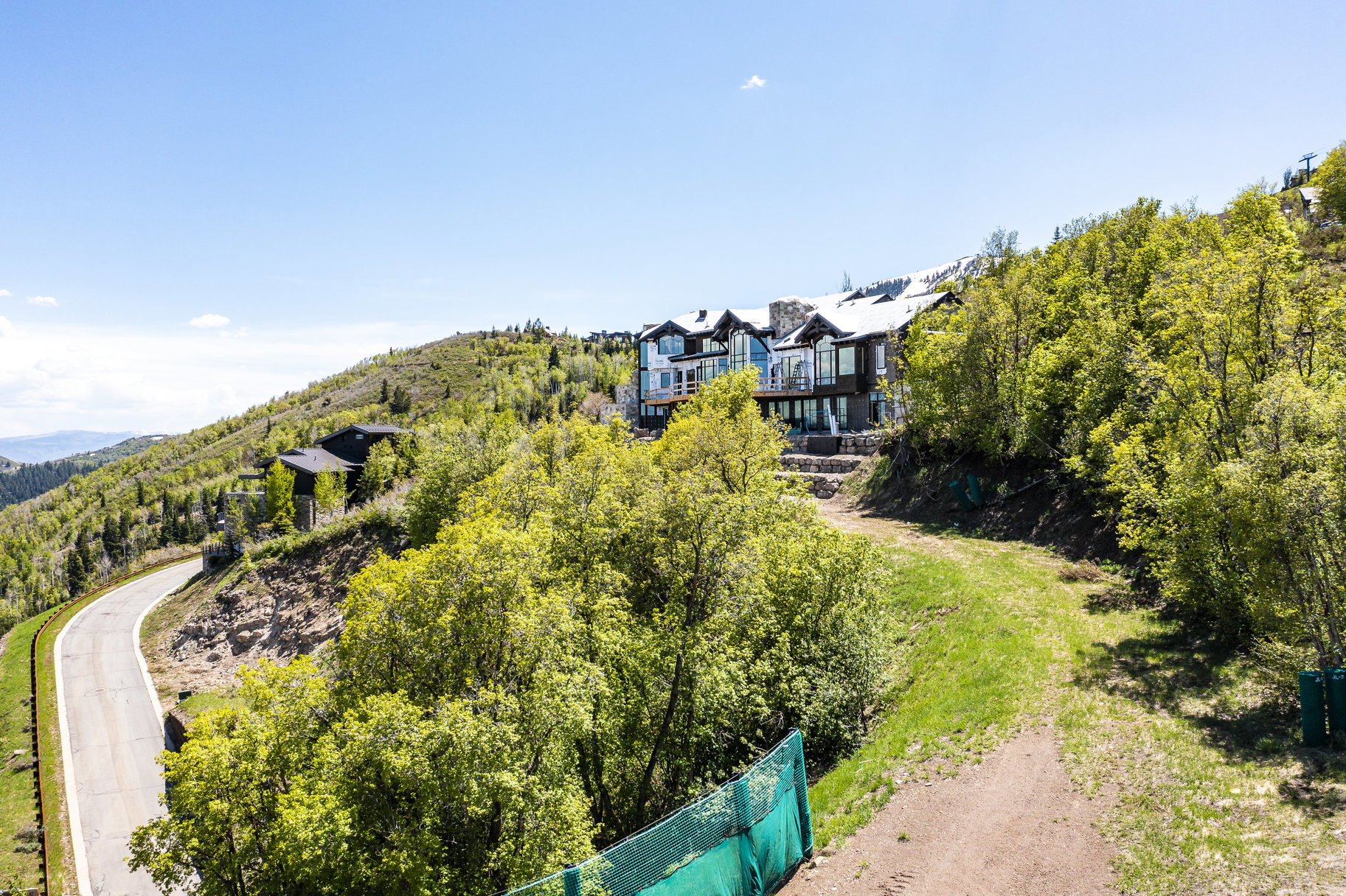 Hillside property featuring multi-level architecture with extensive glazing, stone accents, and a prominent deck