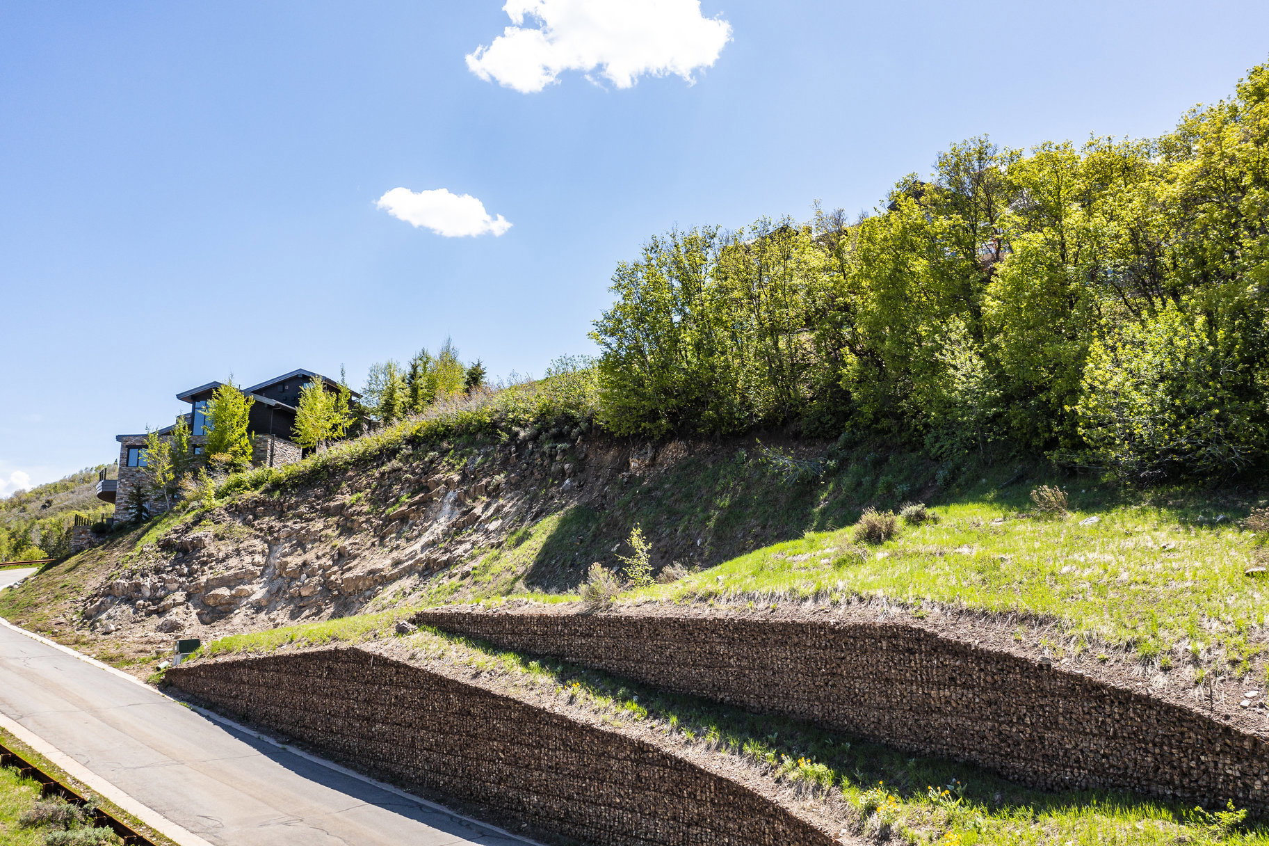 Modern architectural residence situated on a sloped hillside, featuring dark siding and expansive windows