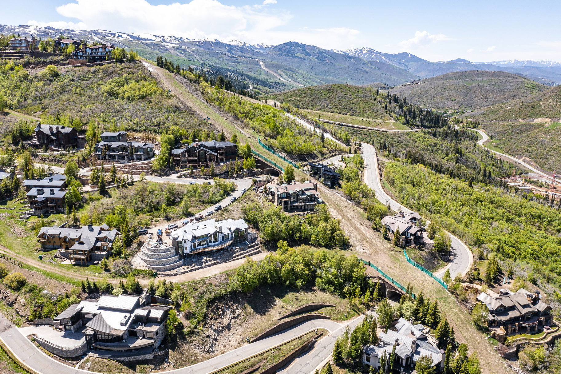 Mountainous landscape featuring residential properties and winding roadways, with distant snow-capped peaks