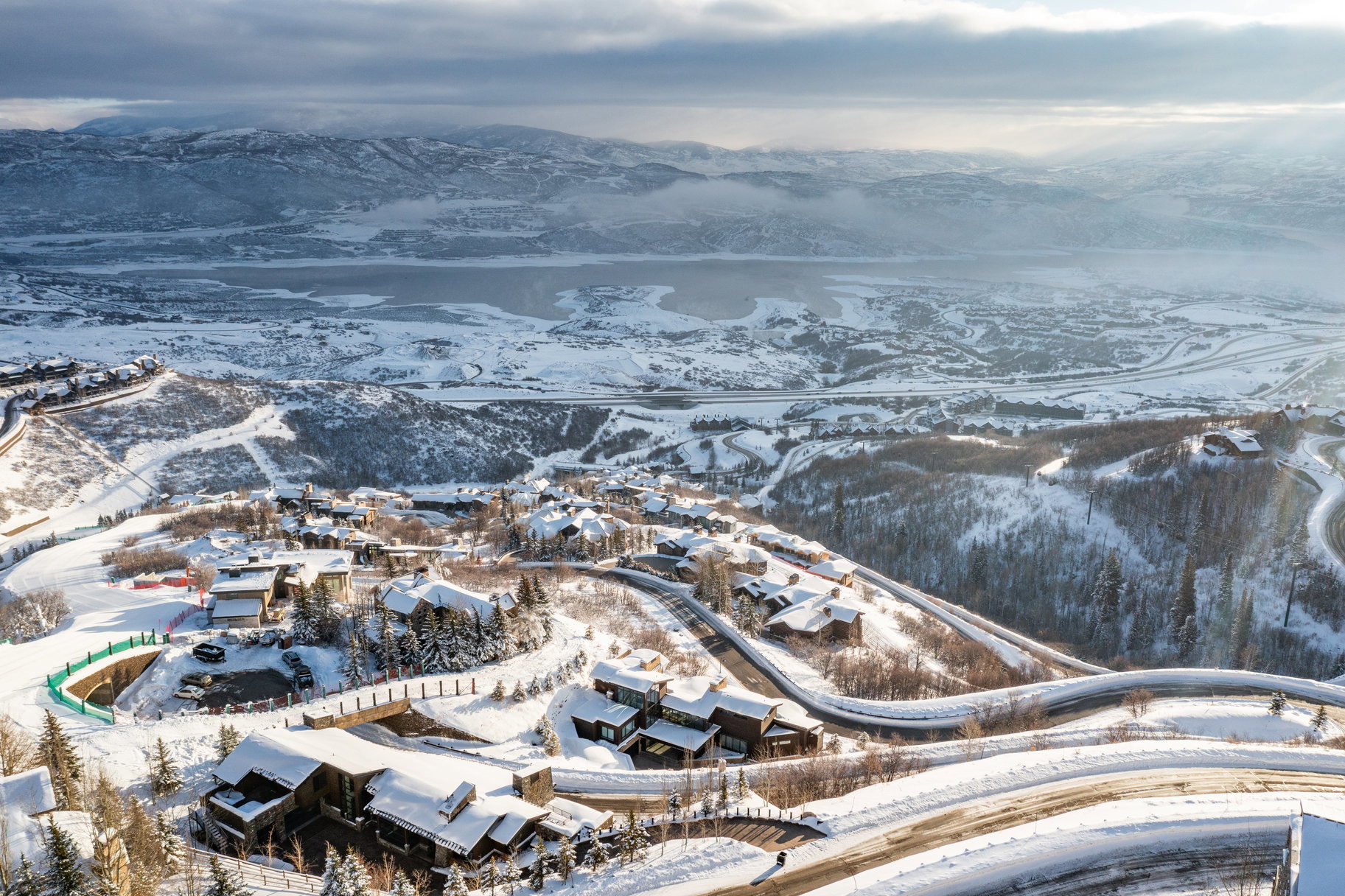 Expansive snow-covered mountain landscape with a body of water in the distance