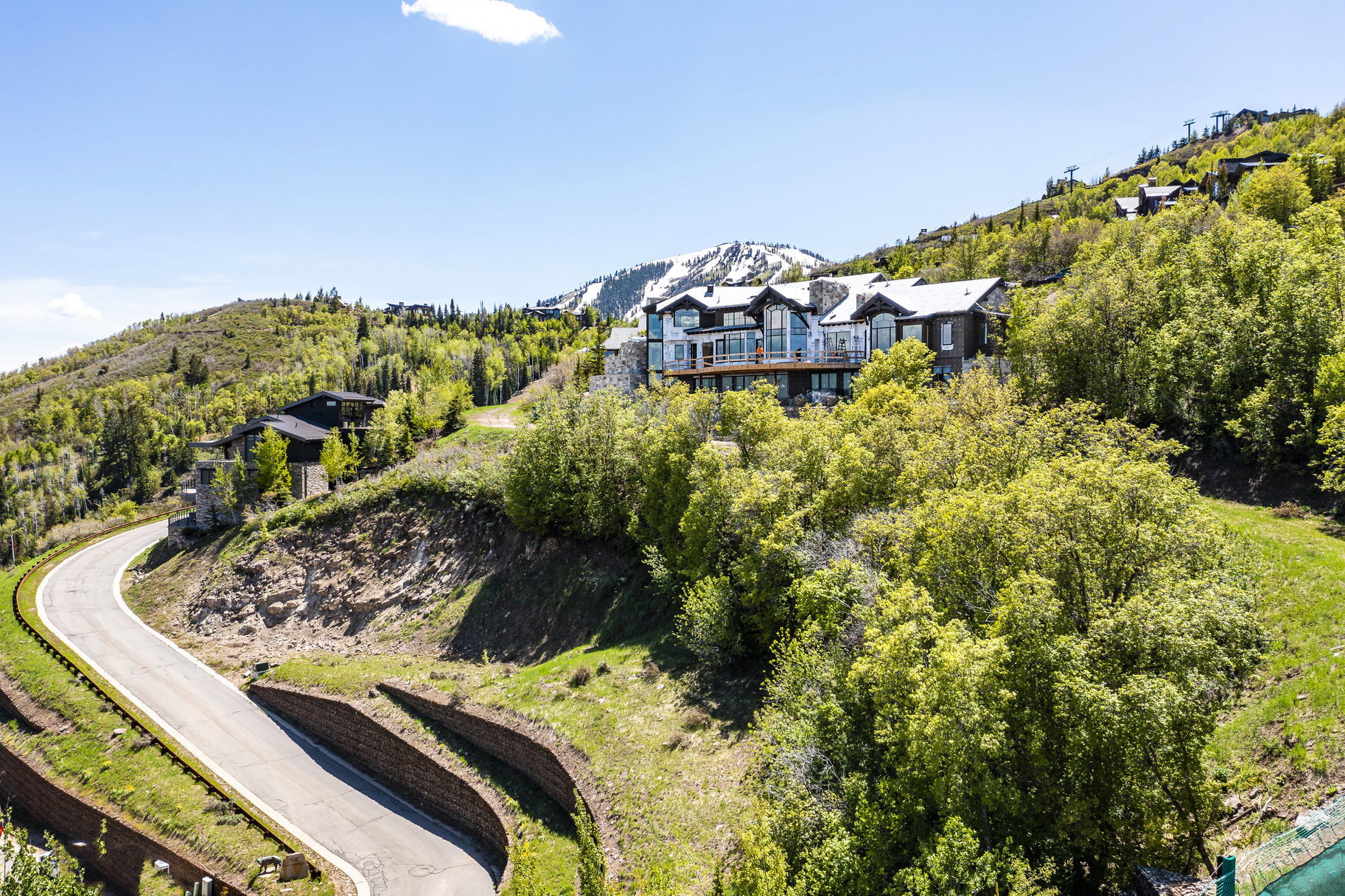 Hillside residence featuring stone and wood siding, multiple exterior balconies, and a snow-capped mountain backdrop