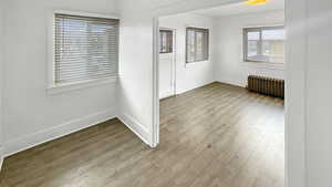 Spare room featuring radiator heating unit and light wood-style flooring