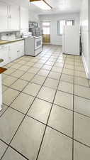 Laundry area with light tile patterned floors, a textured ceiling, and water heater
