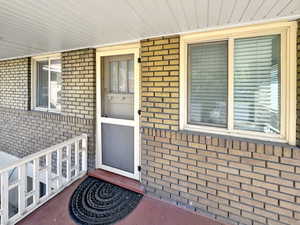 Doorway to property with brick siding and a porch