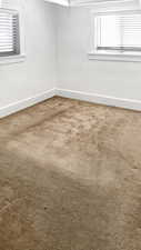 Empty room featuring light carpet and baseboards