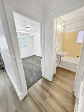 Corridor featuring light wood-style flooring and a textured ceiling