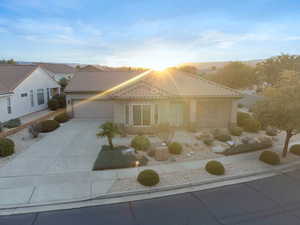 View of front facade featuring driveway, stucco siding, a garage, a tiled roof, and a porch