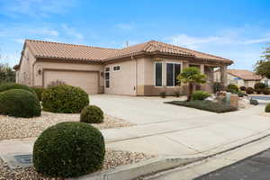 View of front of home with stucco siding, concrete driveway, an attached garage, and a tiled roof
