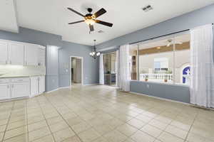Unfurnished living room featuring a ceiling fan, hanging lights, and light tile patterned flooring