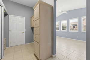 Hallway with vaulted ceiling and light tile patterned flooring