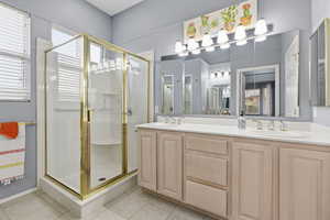 Full bathroom featuring a shower stall, double vanity, and light tile patterned floors