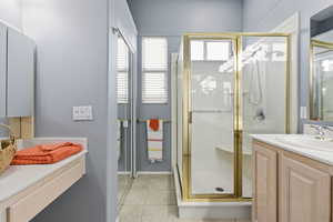 Full bath with vanity, a shower stall, light tile patterned floors, and a textured wall