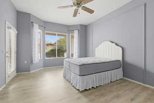 Bedroom with light wood-type flooring, a ceiling fan, and access to exterior