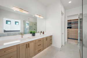 Bathroom with a spacious closet, double vanity, a tile shower, and recessed lighting