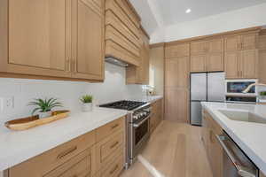 Kitchen with stainless steel appliances, light stone counters, decorative backsplash, light wood finish cabinetry, and recessed lighting