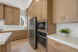 Kitchen with decorative backsplash, stainless steel appliances, and light wood-type flooring