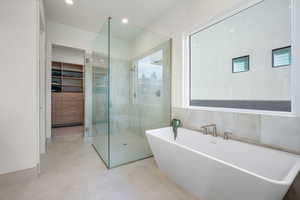 Full bath with a shower stall, a walk in closet, a freestanding tub, and recessed lighting