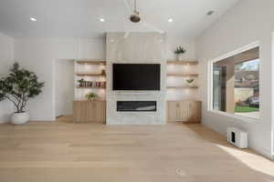 Unfurnished living room with a ceiling fan, light wood-style floors, a premium fireplace, and recessed lighting