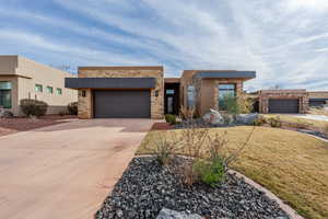 Contemporary house with driveway, stucco siding, a front yard, and an attached garage
