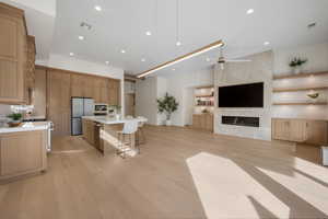 Kitchen with a kitchen bar, open floor plan, stainless steel appliances, a kitchen island with sink, and light wood finished floors