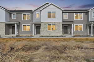 Back of house at dusk with stone siding