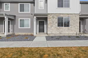 Property entrance with stone siding and a lawn