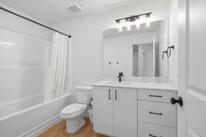 Full bathroom featuring light wood finished floors, shower / bathtub combination with curtain, and vanity