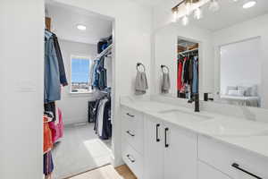 Walk in closet featuring a sink and light colored carpet