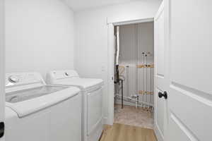 Laundry room featuring independent washer and dryer and light wood-style flooring