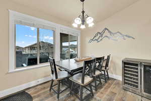 Dining room with wine cooler, suspended lighting, wood finished floors, and vaulted ceiling