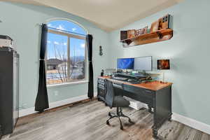 Home office with lofted ceiling and light wood-type flooring