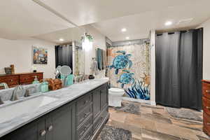 Full bath featuring double vanity, recessed lighting, and light stone finish floors