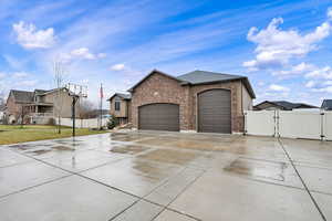 View of front of property featuring a gate, an attached garage, driveway, and brick siding