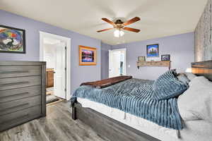 Bedroom featuring wood finished floors, ceiling fan, and ensuite bath