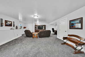 Living area with a desk, carpet flooring, and a textured ceiling