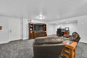 Living room featuring carpet flooring, an office area, and a textured ceiling