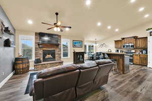Living area with lofted ceiling, recessed lighting, a fireplace, dark wood-style floors, and a ceiling fan