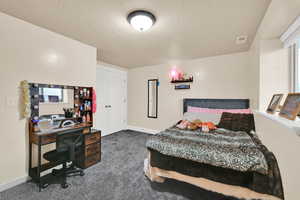 Bedroom featuring carpet, a textured ceiling, and a desk