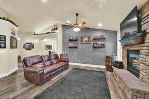 Living area featuring wood finished floors, ceiling fan, a fireplace, arched walkways, and recessed lighting