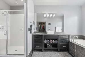 Bathroom featuring a spacious closet, a stall shower, vanity, a garden tub, and light tile patterned floors