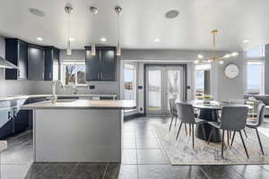 Kitchen featuring light countertops, an island with sink, and suspended lighting
