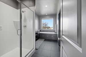 Full bath featuring a stall shower, a garden tub, dark tile patterned flooring, recessed lighting, and a textured ceiling