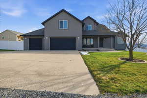 Traditional-style house with roof with shingles, stucco siding, concrete driveway, an attached garage, and a porch