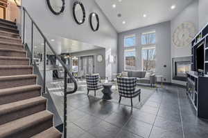Living room featuring recessed lighting, a high ceiling, a glass covered fireplace, and dark tile patterned flooring