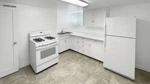 Kitchen featuring white appliances, white cabinetry, and light countertops
