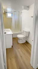 Full bath with vanity, shower / tub combo, and light wood-style floors