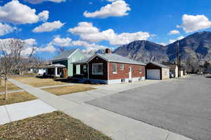 View of front facade featuring a mountain view, a garage, a chimney, brick siding, and concrete driveway