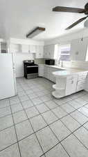Kitchen with decorative backsplash, freestanding refrigerator, stainless steel electric range oven, and white cabinetry