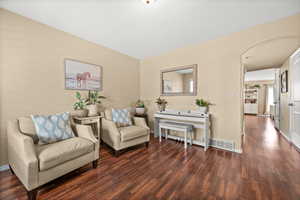 Sitting room featuring arched walkways and dark wood-type flooring